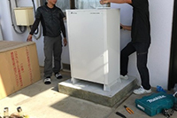 かさ上げした基礎の上に蓄電池を設置するスタッフ